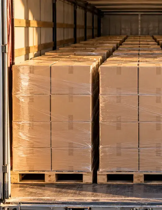 Camion complet : trois rangées de palettes de cartons filmés, chargées dans la remorque.